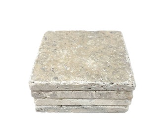 Op de afbeelding: Een stapel van zes beige stenen onderzetters met een ruw, getextureerd oppervlak.