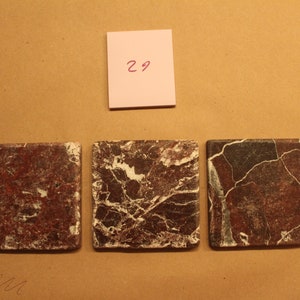 May include: Three square ceramic tiles with a brown and white marbled pattern. The tiles are arranged in a row.