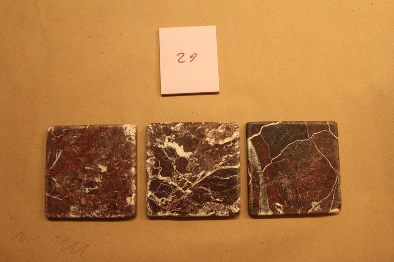 May include: Three square ceramic tiles with a brown and white marbled pattern. The tiles are arranged in a row.