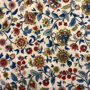May include: A white fabric with a repeating pattern of blue, red, and green floral designs. The pattern is reminiscent of a traditional paisley design.