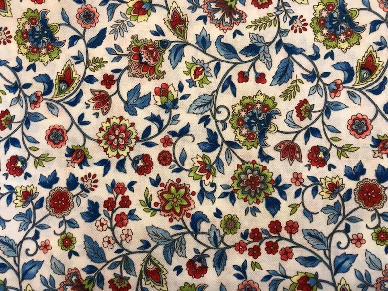 May include: A white fabric with a repeating pattern of blue, red, and green floral designs. The pattern is reminiscent of a traditional paisley design.