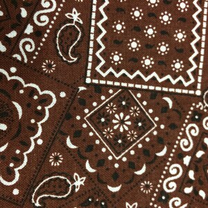 May include: Brown bandana fabric with a white paisley pattern. The fabric has a woven texture.