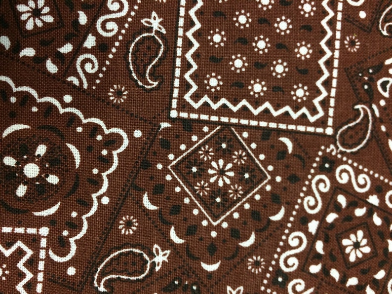 May include: Brown bandana fabric with a white paisley pattern. The fabric has a woven texture.