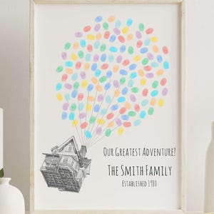 Puede incluir: Impresi&oacute;n art&iacute;stica enmarcada con una ilustraci&oacute;n de una casa unida a un grupo de huellas dactilares de colores, que se asemejan a globos. El texto dice: "Our Greatest Adventure! The Smith Family Established 1980."
