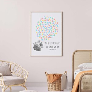 Puede incluir: Una impresi&oacute;n enmarcada con un marco de madera clara. La impresi&oacute;n presenta una ilustraci&oacute;n de una casa con un grupo de huellas dactilares de colores encima. El texto dice "Our Greatest Adventure! The Smith Family Established 1985."