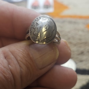 May include: A silver-toned ring crafted from a 1959 United States dime coin. The coin face features the profile of Franklin D. Roosevelt, the word LIBERTY, the phrase IN GOD WE TRUST, and the year 1959. The band is formed by the coin's edge.