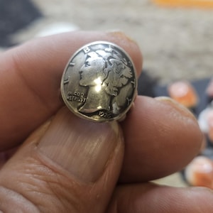 May include: A silver ring featuring a 1926 Mercury dime coin as the centerpiece. The coin displays the profile of Liberty facing left, with the text LIBERTY, IN GOD WE TRUST, and the year 1926 clearly visible on the metallic surface of the coin.