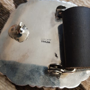 May include: Silver belt buckle with a detailed design. The back of the buckle is stamped with "sterling" and "Indian Jewelry".