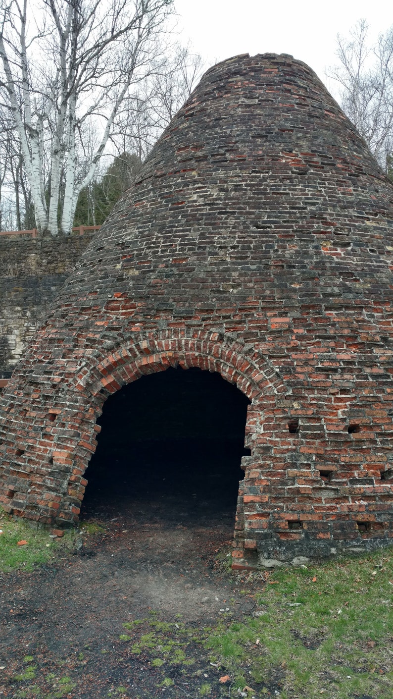 Puede incluir: Una gran estructura c&oacute;nica de ladrillo con un exterior desgastado de color rojo oscuro y marr&oacute;n, con juntas de mortero visibles y una amplia abertura arqueada en la base. La estructura est&aacute; construida con ladrillos envejecidos.