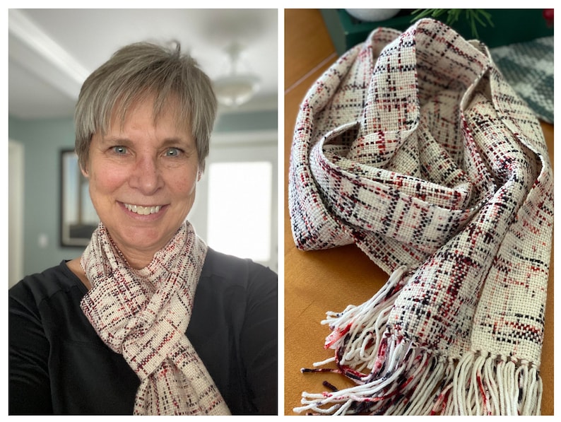 May include: A cream-colored woven scarf with a plaid pattern in red and black. The scarf has a fringed edge. The scarf is wrapped around a person's neck in one image and displayed on a surface in another image.