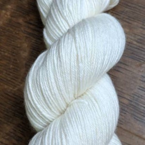 May include: A skein of white yarn, a soft and fluffy material for knitting or crocheting.