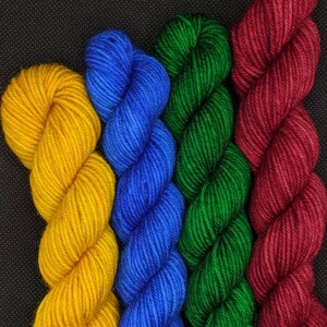 Puede incluir: Cuatro ovillos de hilo en diferentes colores: amarillo, azul, verde y rojo.