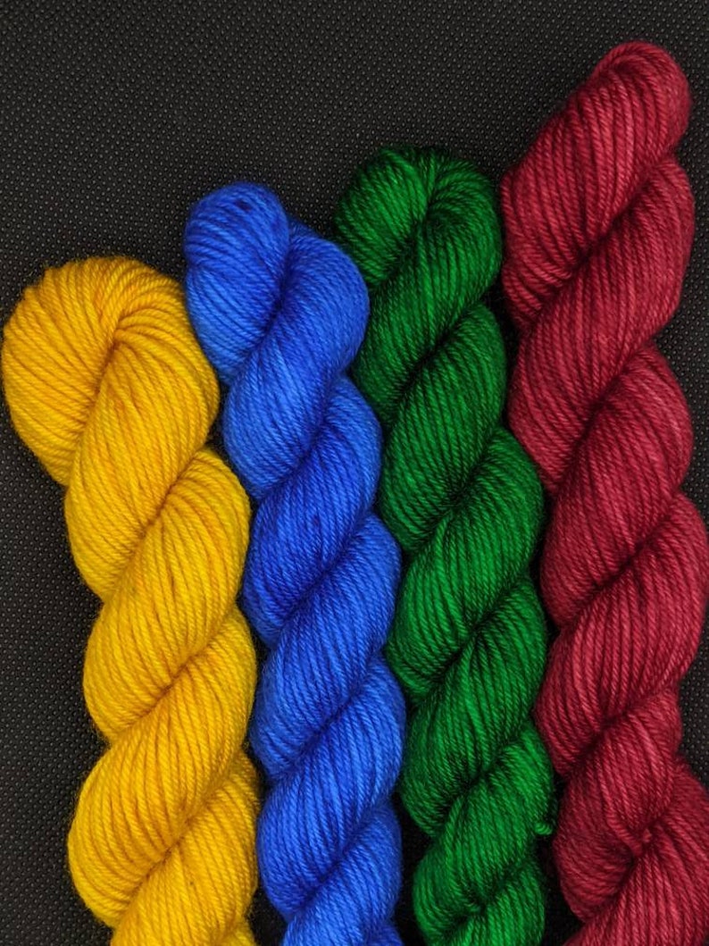 Puede incluir: Cuatro ovillos de hilo en diferentes colores: amarillo, azul, verde y rojo.