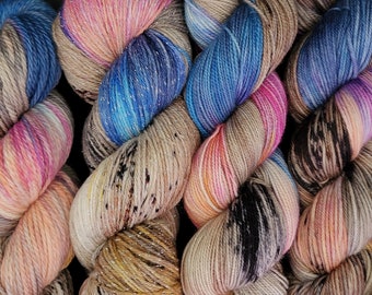May include: Four skeins of yarn in different color combinations. The yarn is a mix of beige, pink, blue, and black with silver glitter throughout.