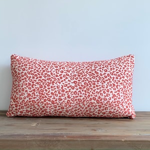 May include: A rectangular red and white patterned throw pillow with a leopard print design.