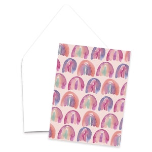 May include: A card with a repeating pattern of watercolor rainbows in shades of pink, purple, blue, and orange on a light pink background.