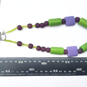 Puede incluir: Collar hecho a mano con cierre plateado. Cuenta con cuentas cil&iacute;ndricas verdes, cuentas cuadradas moradas y cuentas redondas moradas oscuras. El collar mide aproximadamente 46 cm de largo.