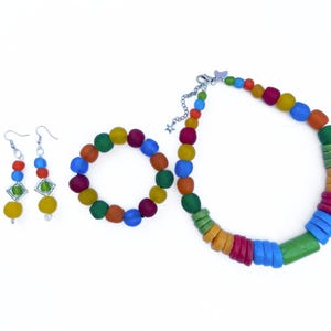 A vibrant jewellery set comprising a necklace, bracelet, and earrings laid out next to each other on a white background. The necklace, bracelet and earrings are all made of a rainbows colours including green, blue, yellow, green and orange. The findings are silver plated and the bracelet is elasticated.