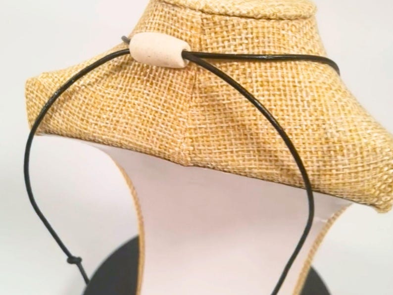 A black necklace with a light-coloured wooden bead clasp. The necklace is displayed on a burlap-covered bust. The cord is made from vegan leather. The bust is on a white surface.