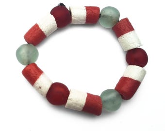 May include: A circular bracelet composed of alternating cylindrical beads and spherical beads. The cylindrical beads feature a red and white striped pattern, while the spherical beads are either a solid matte red or a translucent pale seafoam green.