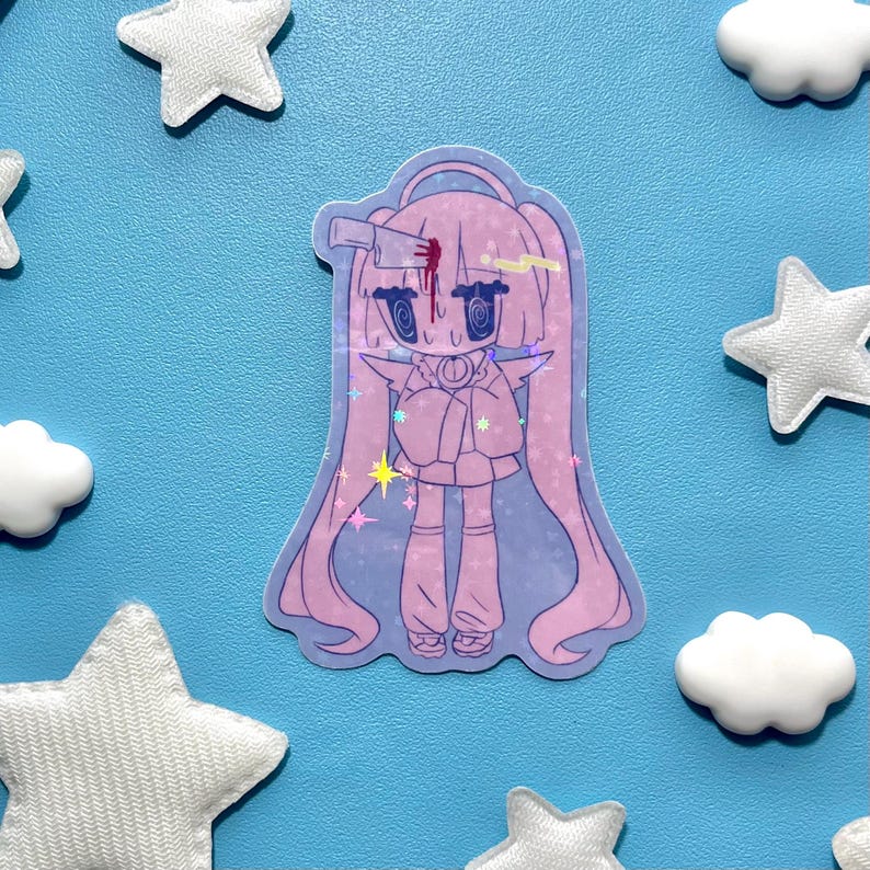 May include: A holographic sticker featuring a cartoon character with long pink hair, a pacifier, and a bandage on its head. The sticker has a light blue background with white star and cloud decorations.