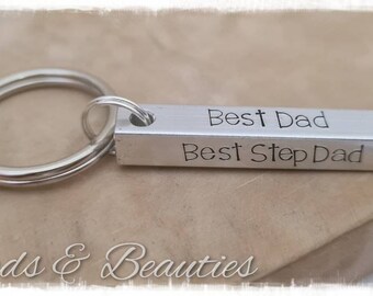 May include: Silver keychain with a rectangular bar engraved with the text "Best Dad Best Step Dad".