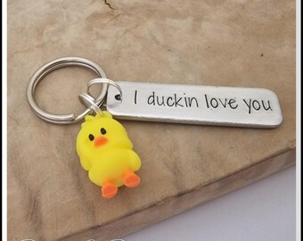 May include: A silver keychain with a yellow rubber duck charm and a silver tag that reads "I duckin' love you".