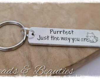 May include: Silver keychain with a small silver tag that reads "Purrfect Just the way you are" with a small cartoon cat illustration.