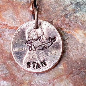 May include: A copper key chain with a 2021 US penny featuring an engraved orca whale and the name "STAN".