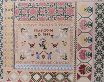 May include: A framed sampler with a colorful cross-stitch design. The sampler includes a date, "Marzo 14 D 1849", and the text "Por Antonia de Cruzba".