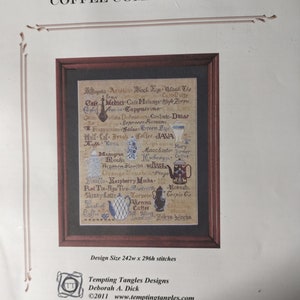 May include: A framed cross-stitch sampler titled "Coffee Compendium" featuring various coffee drinks and related illustrations. The design includes text and images of coffee pots and cups. The design size is 242w x 296h stitches.