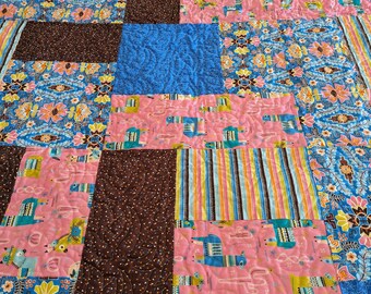 May include: A patchwork quilt with a variety of colorful fabrics, including pink, blue, brown, and yellow. The quilt features a pattern of llamas and cacti.
