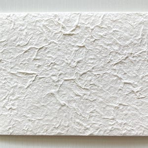 May include: A white textured paper card with a rough, uneven surface.