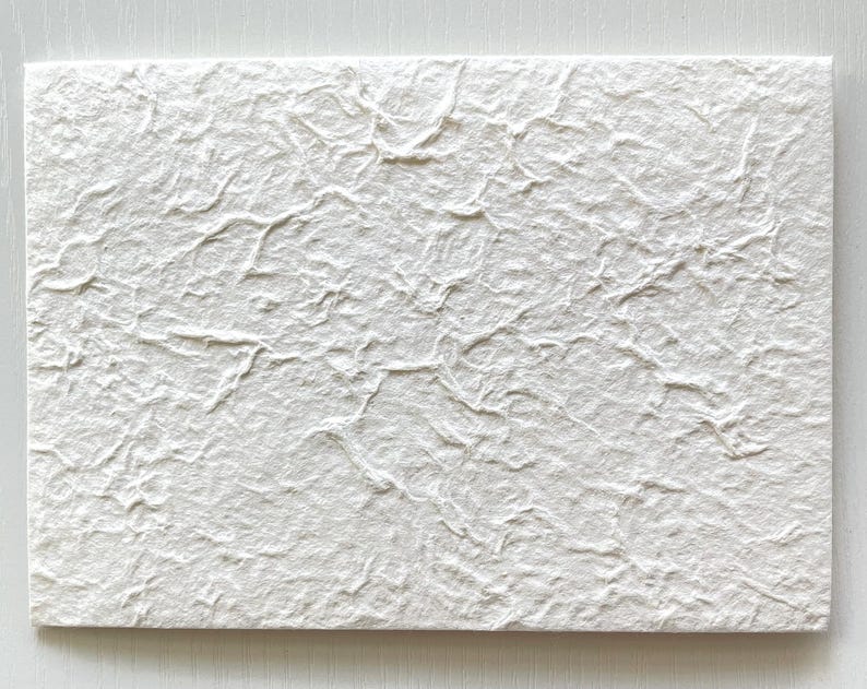 May include: A white textured paper card with a rough, uneven surface.