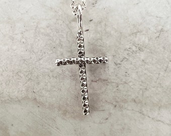Puede incluir: Un collar de cadena de plata con un colgante de cruz de plata texturizado.