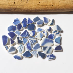 Peut inclure: Une collection de petits morceaux de verre de mer en céramique bleu et blanc. Les morceaux sont de forme irrégulière et présentent une variété de motifs.