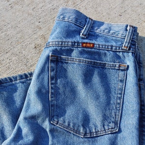 May include: A pair of blue denim jeans with a back pocket and a brown leather label that reads "Lee" on the back waistband.