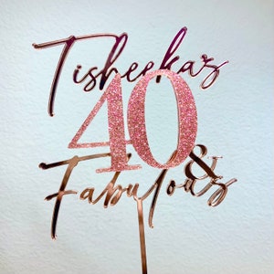 May include: Rose gold glitter cake topper with the text "Cheers to 40 & Fabulous".
