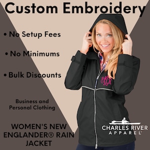 May include: Black rain jacket with a white zipper and a pink monogram on the chest. The jacket has a hood and a white logo on the bottom right corner that says "Charles River Apparel".