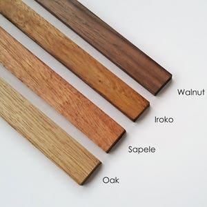 May include: Four wood samples, from left to right: Oak, Sapele, Iroko, and Walnut. The wood samples are arranged in a diagonal line, with the Oak sample at the bottom left and the Walnut sample at the top right.