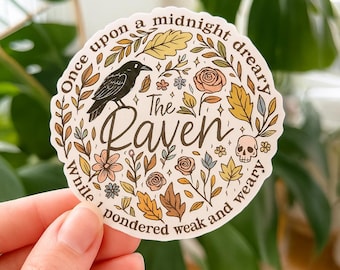 May include: A circular sticker featuring a black raven, a small skull, and various autumn-colored flowers and leaves. The text reads: Once upon a midnight dreary, The Raven, while I pondered weak and weary. The design uses shades of brown, gold, and pink.