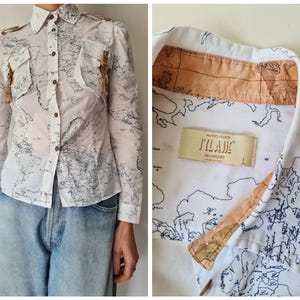 May include: White button-down shirt with a map design in navy blue. The shirt has long sleeves, two chest pockets, and brown buttons. The collar and pocket flaps have a tan accent. The label reads "FILANI".