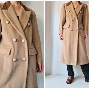 May include: A long, double-breasted camel-colored coat featuring a dark brown velvet collar, six round buttons, and two flap pockets. The coat has a structured silhouette with long sleeves and a notched lapel, extending to mid-calf length.