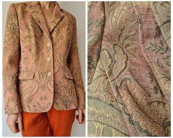 May include: A patterned blazer in shades of peach, gold, and brown. The jacket features a classic two-button closure, notched lapels, and two front pockets. The fabric has an intricate floral design.