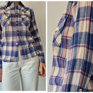 May include: A long-sleeved plaid shirt in blue, cream, and red. The shirt has a button-down front, two chest pockets, and buttoned cuffs. The plaid pattern is a classic design, suitable for casual wear.