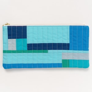 May include: A blue, green, and gray quilted zippered pouch with a geometric pattern.
