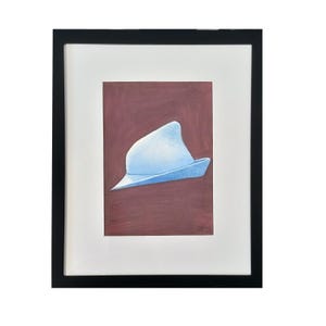May include: A framed artwork featuring a light blue hat against a maroon background. The hat is painted with soft shading, giving it a three-dimensional appearance. The artwork is framed in a black frame with a white mat.