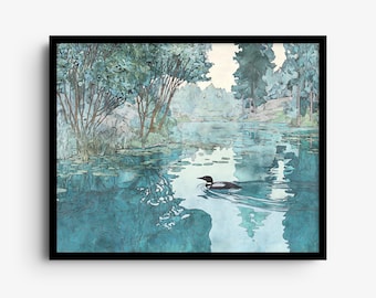 May include: A framed watercolor painting depicting a black and white loon swimming on a calm blue lake. The scene features lush green trees along the shoreline, lily pads on the water surface, and soft reflections, all enclosed in a black frame.