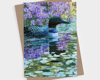 Tarjetas plegables en blanco con diseño de colimbo nadando con aster morado, papelería colorida con motivos botánicos de aves.