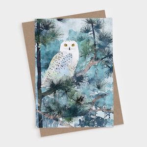 May include: A rectangular greeting card featuring a watercolor illustration of a white snowy owl with black spots and yellow eyes perched on a pine tree branch. The background consists of blue and green pine needles and watercolor washes.